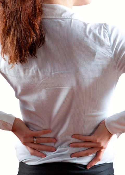 Back view of a person standing with hands on hips, wearing a white long-sleeved shirt against a plain background.