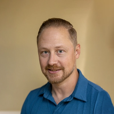 Chiropractor Jeffrey Albing Smiling In Blue Polo
